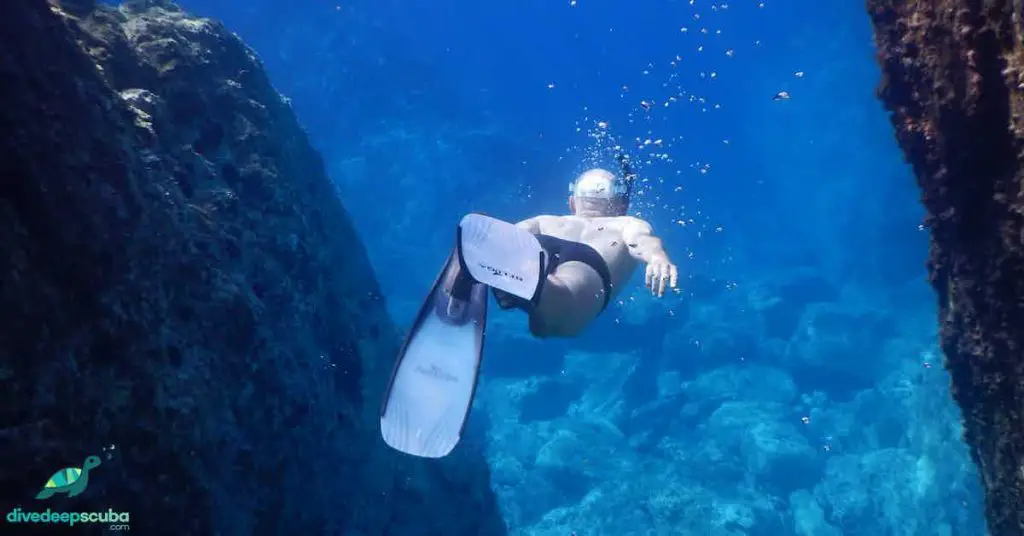 Freediver swimming between two rocks
