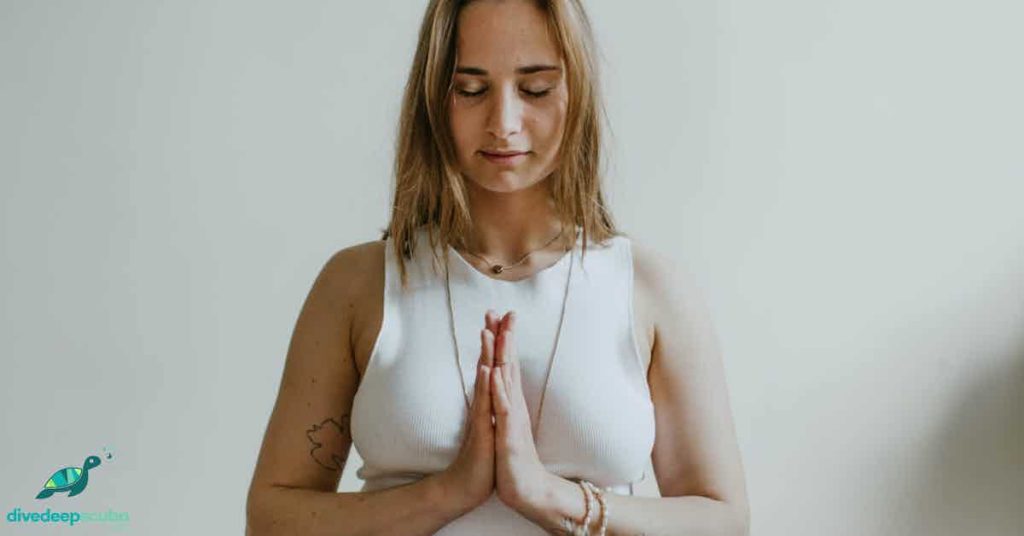 A woman with her hands together, meditating 