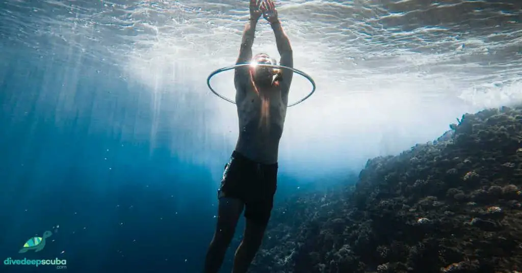 Freediver swimming through a ring of air underwater