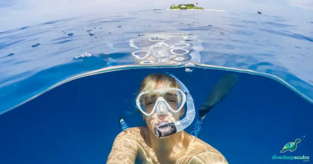 Freediver taking a selfie near the surface with an island behind