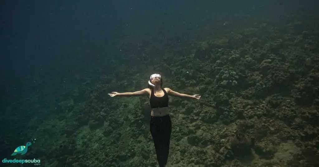 A freediver looking up and reaching for the surface 