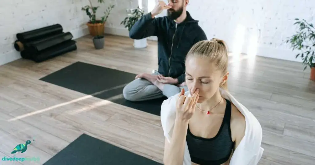 A man and woman practising breathing in yoga class