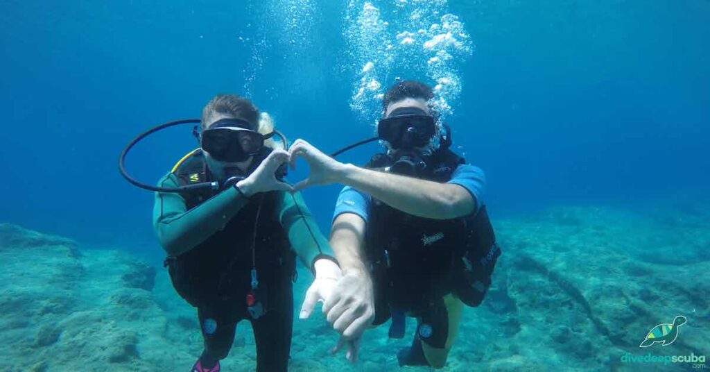 a picture of two scuba divers making heart in mares gear